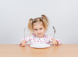 Little girl holding fork and spoon with