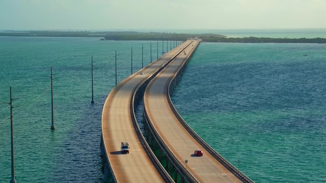 Aerial of 7 mile highway bridge crossing the ocean with traffic moving both directions on a beautiful early morning with green islands in the distance