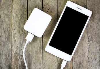 smart phone and adapter charger on wood background