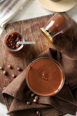 Melted chocolate on glass bowl, on wooden background