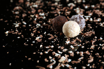 Assorted chocolate candies with flakes on black background