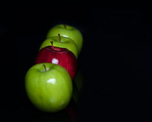 Red and green apple fruit isolated on black background in row