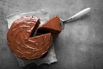 Chocolate cake with a cut piece and blade on gray background, closeup