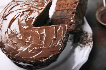 Chocolate cake on plate with a cut piece and fork and cocoa on gray background, closeup