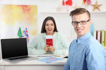 Agent and happy young woman with passport and ticket in the office of travel company