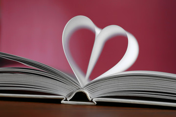 Heart from book pages on red blurred background