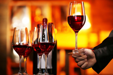 Male hand holding glasses of wine in the bar