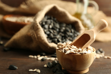 Sunflower seeds in bag and bowl on wooden table background, closeup
