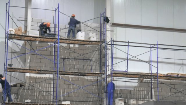 the workers on the scaffolding inside a large and modern warehouse
