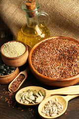 Flax, sesame, pumpkin and sunflower seeds with oil on wooden table background, closeup