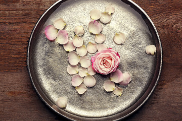 Pink and white rose petals in silver bowl on wooden background