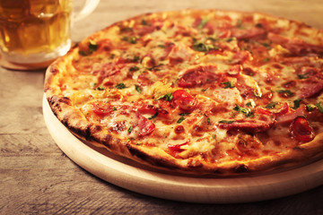 Delicious pizza  and glass of beer are on wooden table, close up