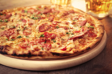 Delicious pizza  and glasses of beer are on wooden table, close up
