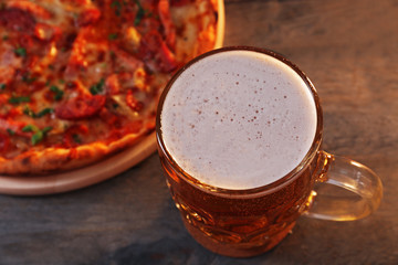 Delicious pizza  and glass of beer are on wooden table