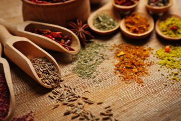Assorted spices in spoons on wooden table closeup