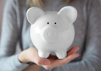 Woman holding in hand white piggy bank