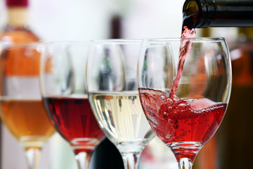 Red wine pouring into glasses, closeup