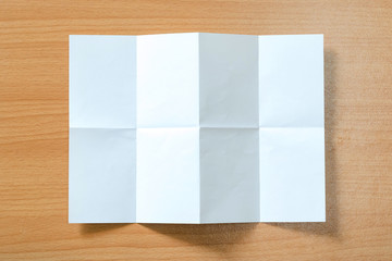 White paper with folds on a wooden floor.