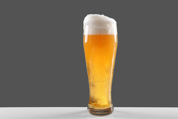 Glass of lager beer on grey background