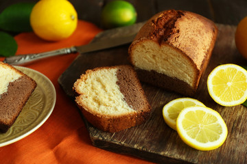 Delicious sweet cake bread with lemons on wooden cutting board closeup