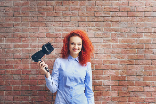 Red haired beautiful girl with hairdryer