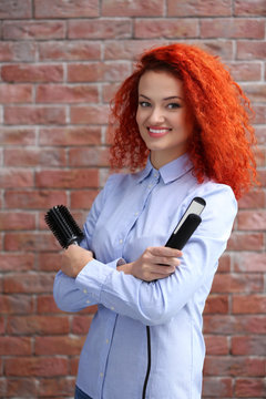 Red haired beautiful girl with comb and hair iron