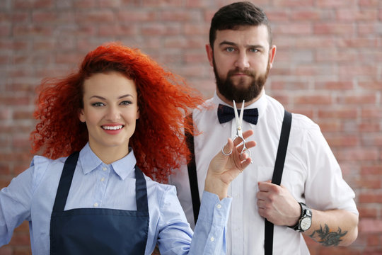 Two professional hairdressers on brick wall background