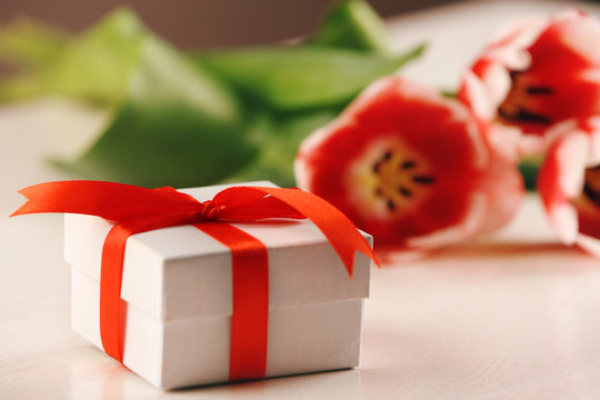 Present box with tulips on wooden table closeup