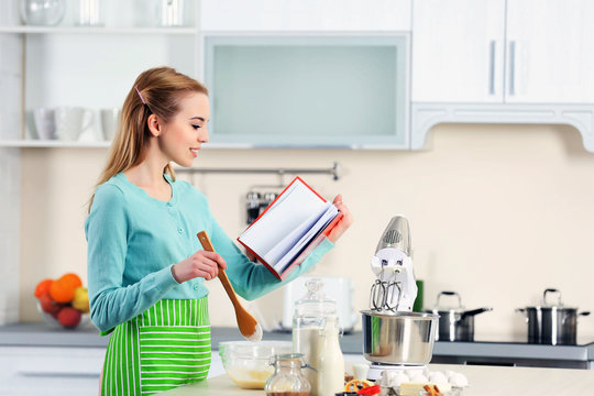 Young Woman Using A Notebook To Follow A Recipe