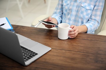 Work concept. Woman using smartphone and drinking tea