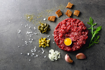 Beef tartare served with an egg yolk on a grey surface, top view
