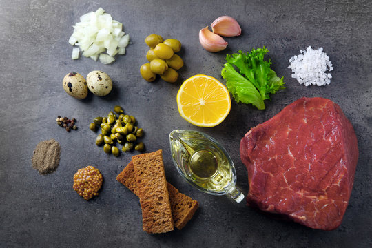 Ingredients for a beef tartare on a black surface, top view