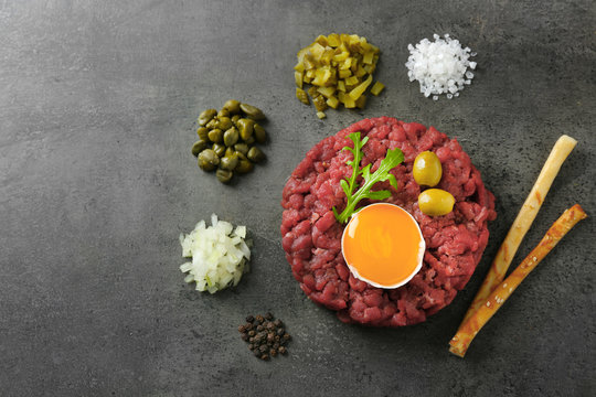 Beef tartare served with bread sticks on a grey surface, top view