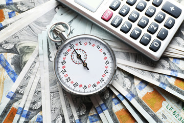 Stopwatch with calculator on dollar banknotes. Time is concept