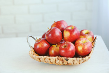Ripe red apples in wicker basket on a kitchen table
