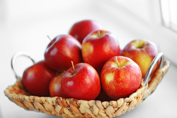 Ripe red apples in a wicker basket on windowsill