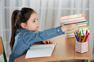 Little girl doing homework at the table in living room