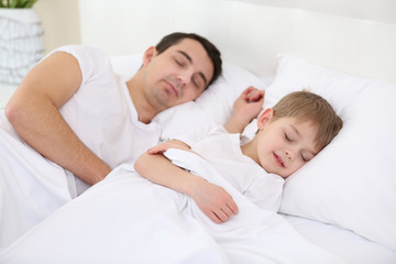 Father and son sleeping in bed at home