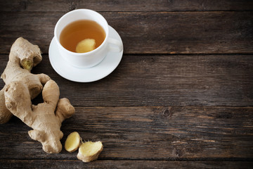 Ginger tea in a white cup on wooden background