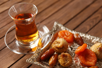 Glass of tea with dried fruits on wooden background
