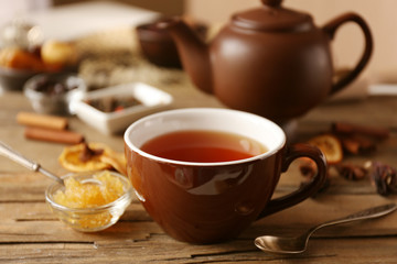 Cup of tea with honey and dried spices on wooden table closeup