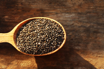 Spoon of chia seeds on wooden background