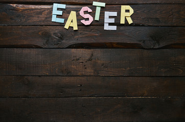 Easter folded paper origami colorful lettering on dark barn wood rustic planks background. Space for text, copy. Postcard template.