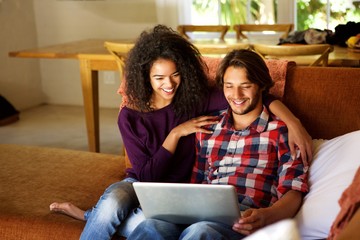 Boyfriend and girlfriend sitting at home with laptop