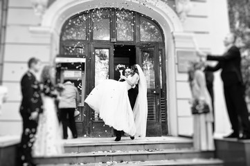 Newlywed couple being showered in rose petals, groom hold his br