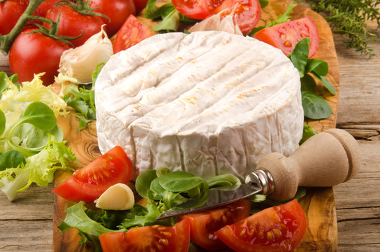 camembert with salad, tomato, garlic and thyme on wooden board