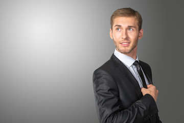 Young handsome businessman adjusting his tie