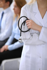 Doctor holding a stethoscope in his hands , the patient on the background