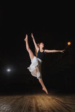 Young brunette dancer girl in split jump