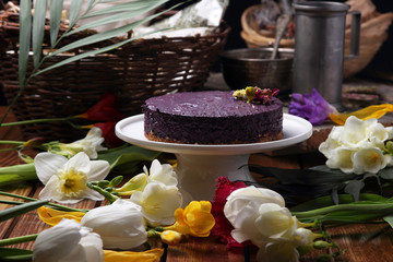 Cake on a plate, standing on the table among the spring flowers..
